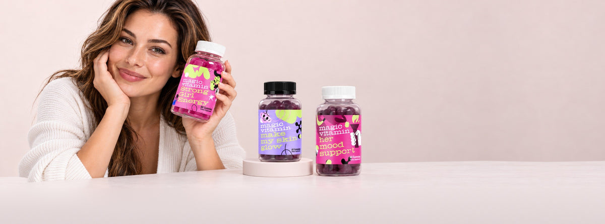 Smiling woman holding Strong Girl Energy gummies, with Make My Skin Glow and Her Mood Support on the table